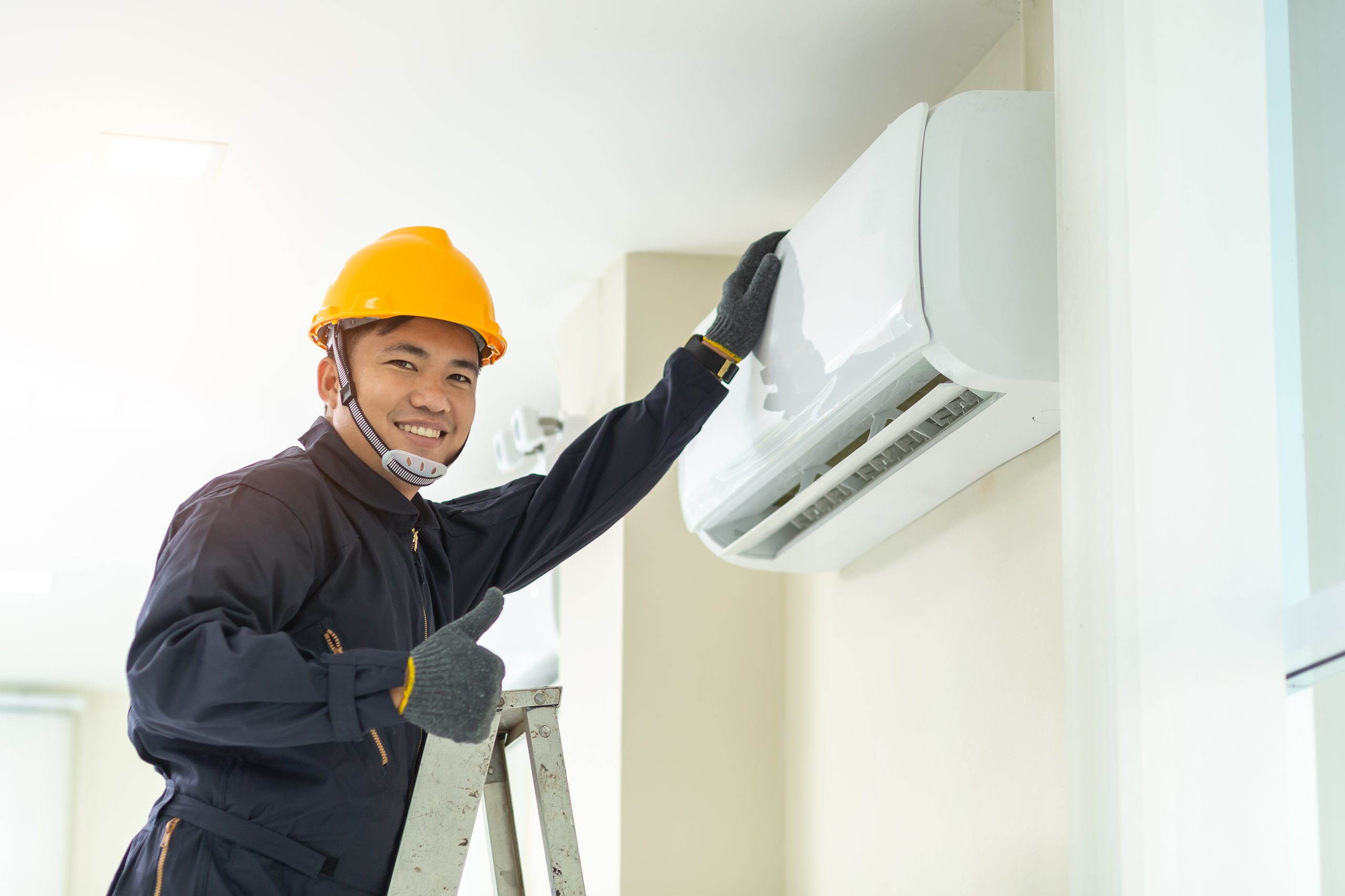 Male technician repairing air conditioner safety uniform indoors